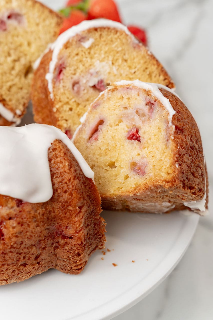 slices of strawberry lemon yogurt cake on a white cake stand