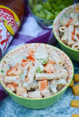 buffalo chicken pasta salad shown served in small green bowls with a drizzle of hot sauce