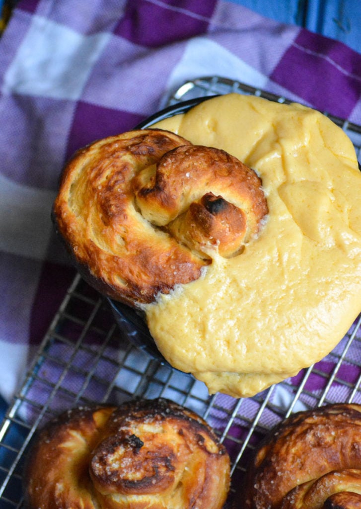 a baked canned biscuit pretzel shown dunked into a bowl overflowing with cheese sauce