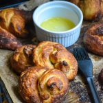 canned biscuit pretzels shown on brown parchment paper with a dish of melted butter