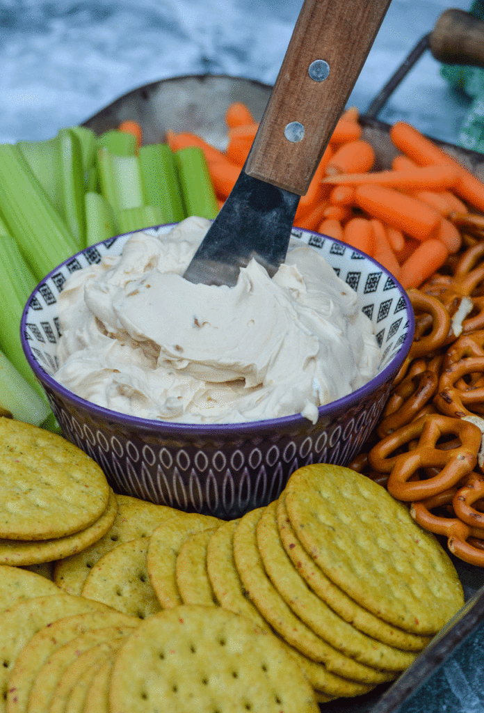 a wooden handled spreader sticking out of a small bowl of homemade french onion dip