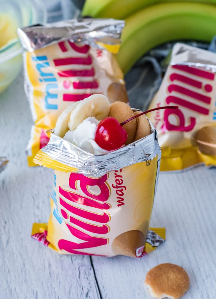 a mini bag of vanilla wafers walking dessert topped with whipped cream, sliced bananas, and a maraschino cherry