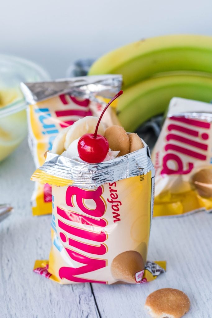 a mini bag of vanilla wafers walking dessert topped with whipped cream, sliced bananas, and a maraschino cherry