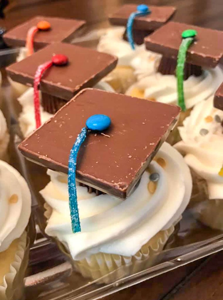 graduation cap cupcakes shown in a clear plastic cupcake holder