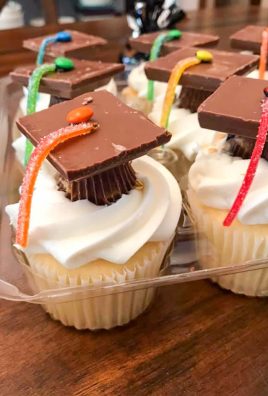 graduation cap cupcakes sitting in a clear plastic cupcake container