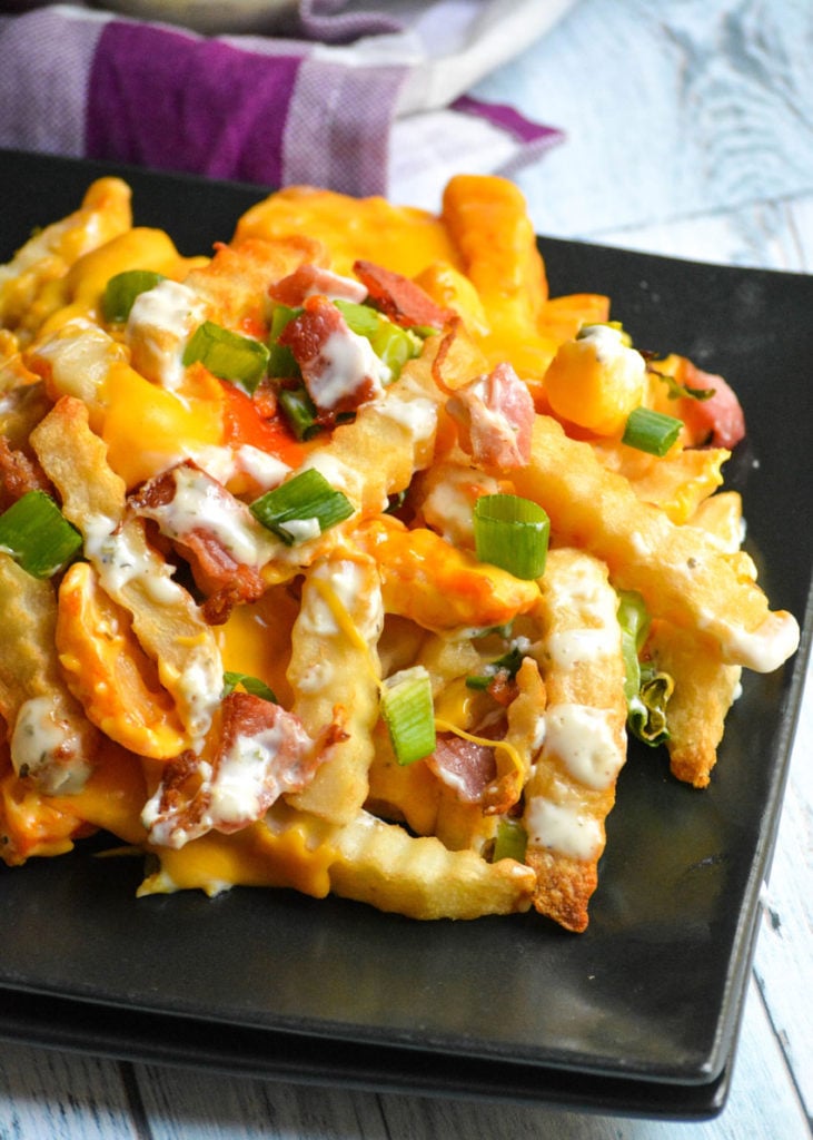 loaded buffalo cheese fries shown on a square black plate