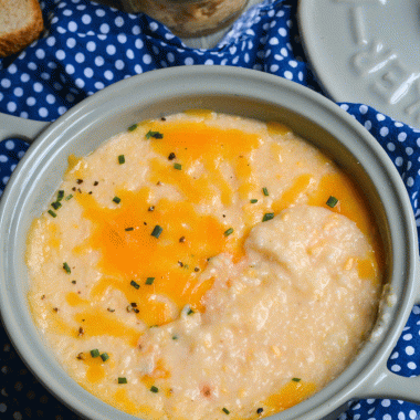 pimento cheese grits served in a gray crock with melted cheddar and chives sprinkled on top