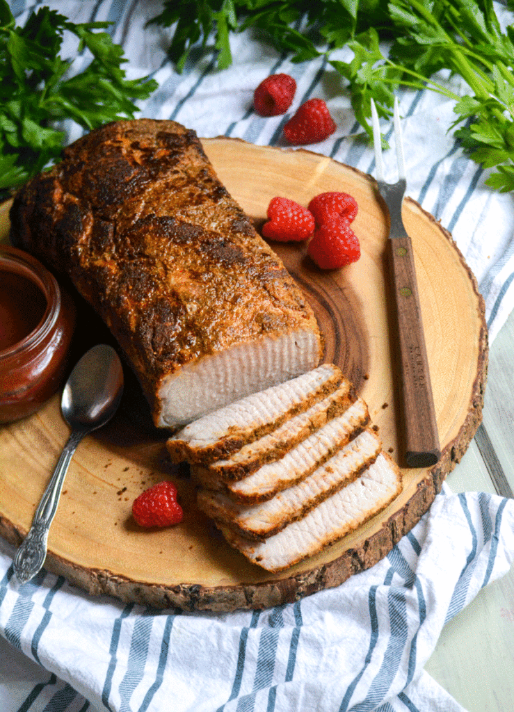 oven baked pork loin shown sliced and served on a wooden cutting board