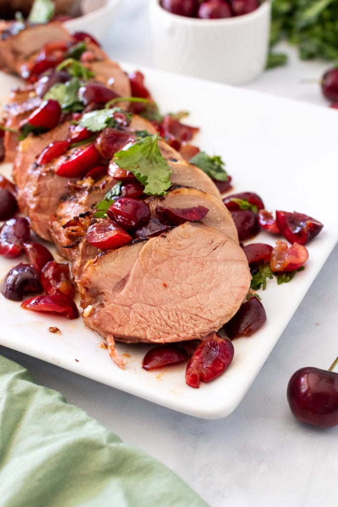 grilled chipotle pork tenderloin topped with cherry salsa & cilantro leaves served on a large white platter