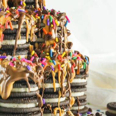 tiktok oreo tower cake covered in creamy peanut butter and rich nutella drizzles with rainbow sprinkles