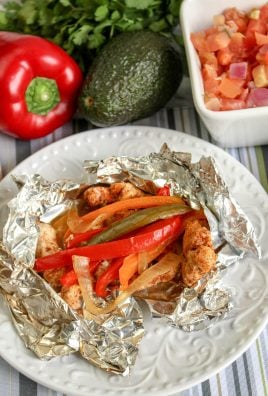 a grilled chicken fajita foil packet shown opened on a white plate