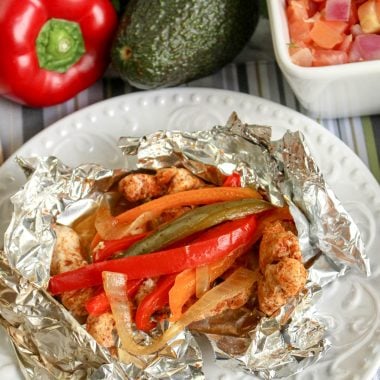 a grilled chicken fajita foil packet shown opened on a white plate