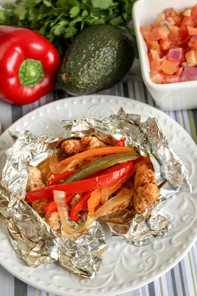 a grilled chicken fajita foil packet shown opened on a white plate