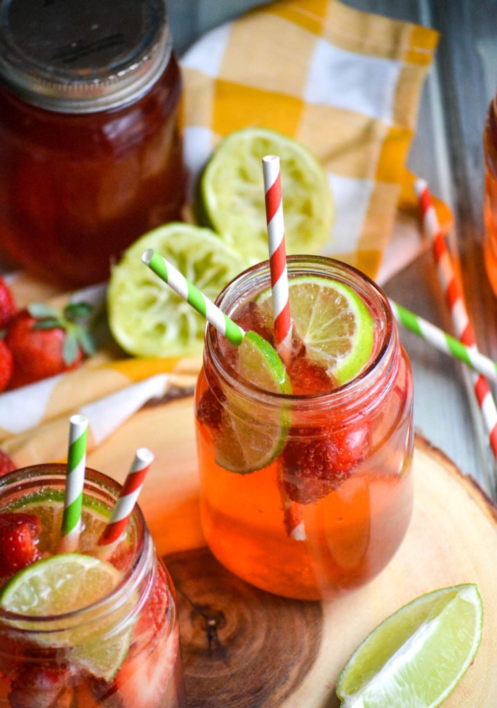copycat sonic strawberry limeade in glass jars on a wooden cutting board