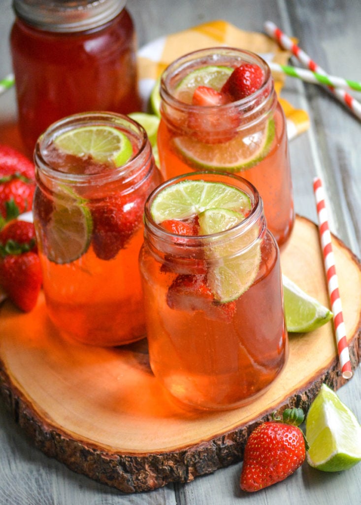 copycat sonic strawberry limeade in glass jars on a wooden cutting board