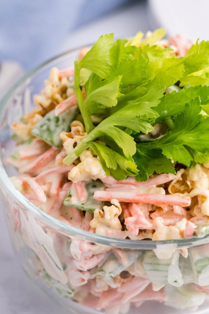 popcorn salad in a glass bowl topped with celery leaves
