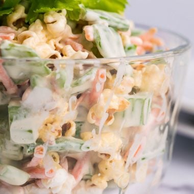 popcorn salad in a glass bowl topped with celery leaves