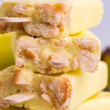 four banana pudding popsicles stacked on top of each other showing the nilla wafer crust and popsicle stick in the bottoms