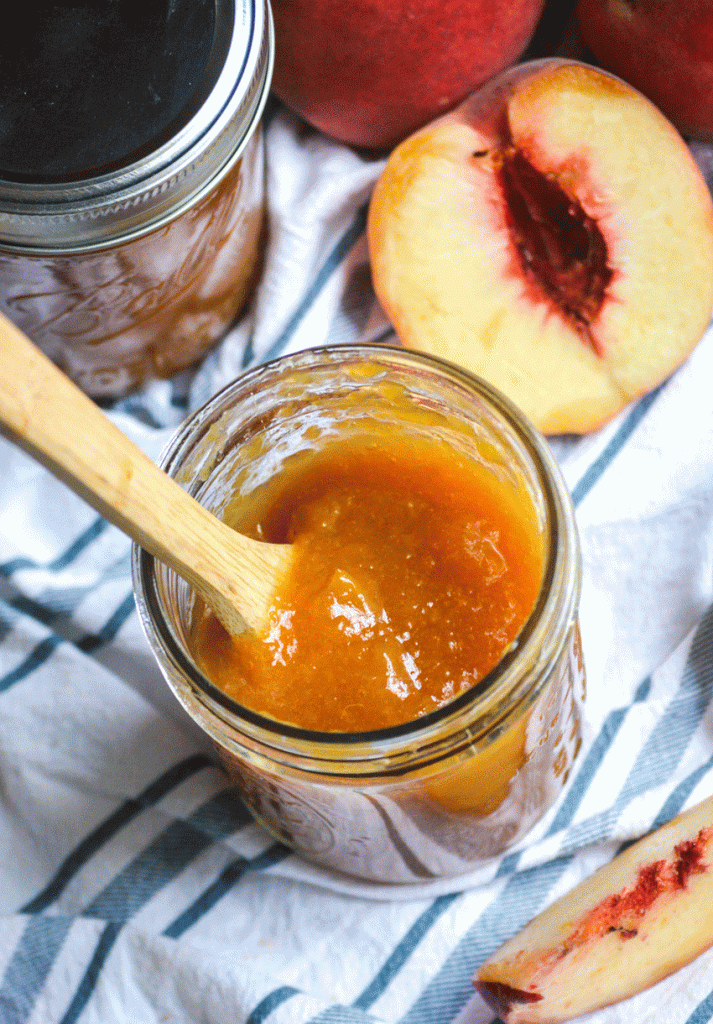 a wooden soon in a glass jar filled with Instant Pot peach jam