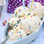 scoops of no churn birthday cake ice cream in an oblong teal dish with sprinkles and candles stuck in them