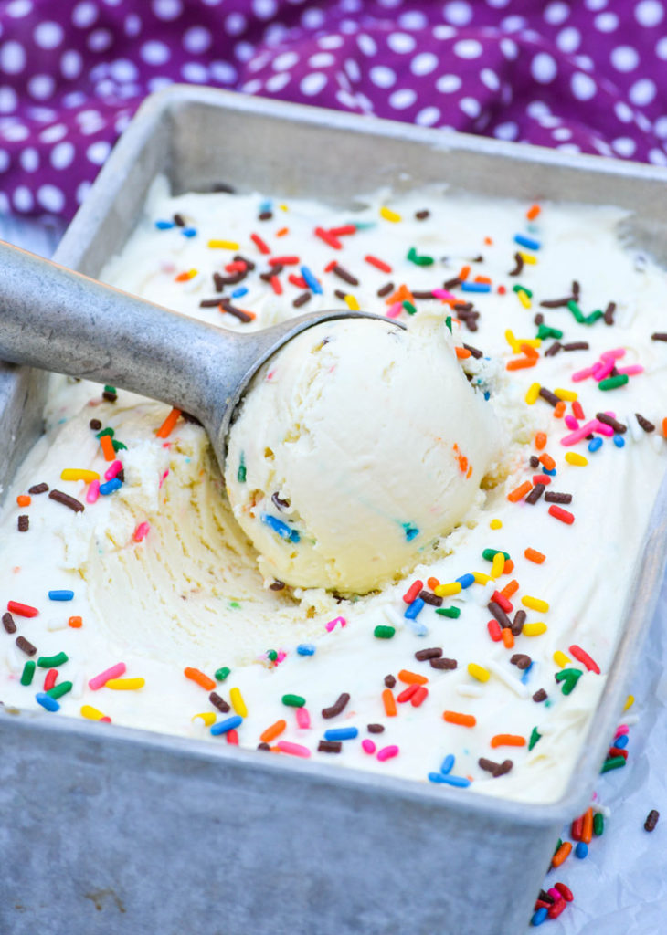 a silver ice cream scoop scooping birthday cake ice cream out of a metal tin