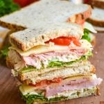 two halves of a Virginia style club sandwich stacked together on a wooden cutting board