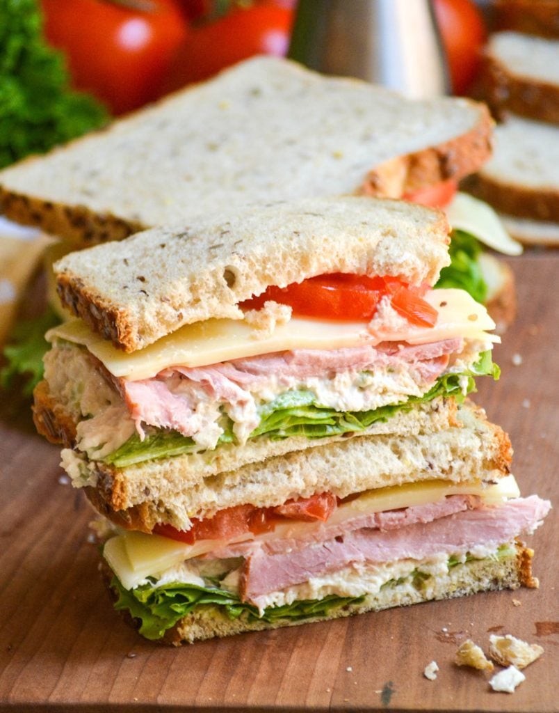 two halves of a Virginia style club sandwich stacked together on a wooden cutting board