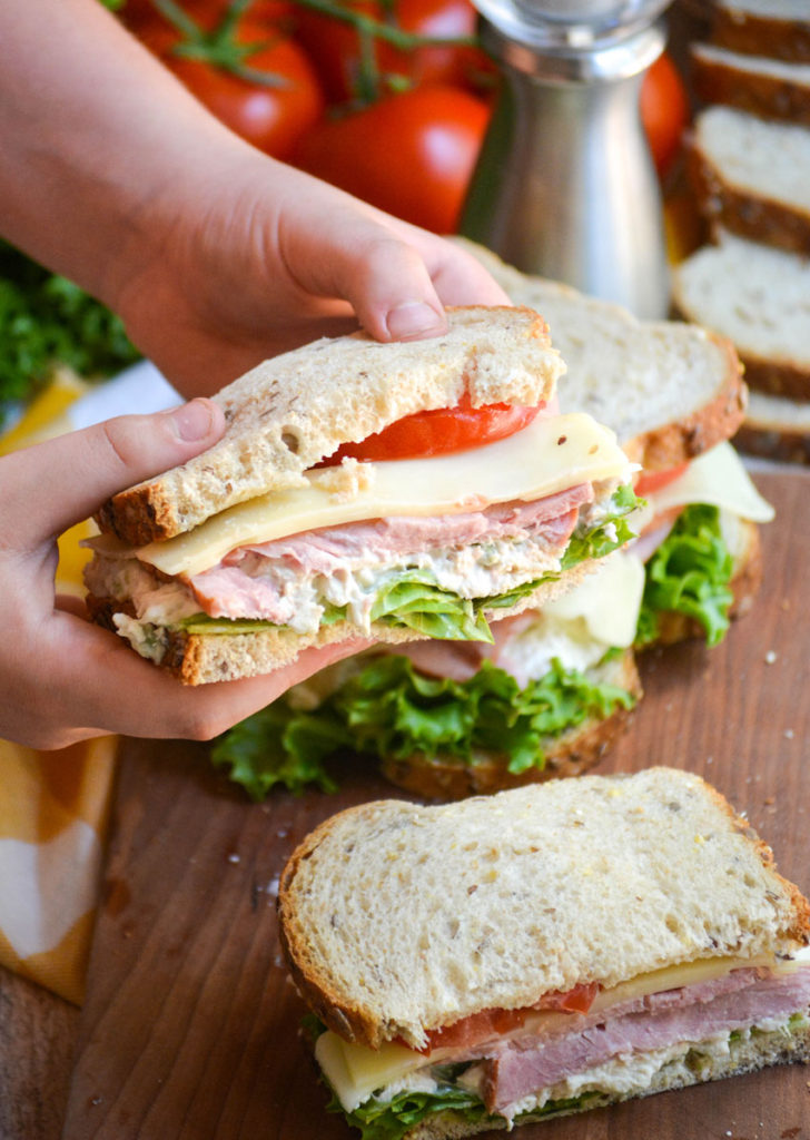 hands holding up a half of a club sandwich made Virginia style