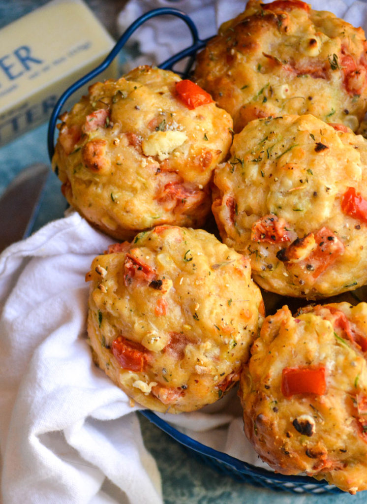 tomato zucchini feta muffins shown in a blue wire basket lined with a white cloth