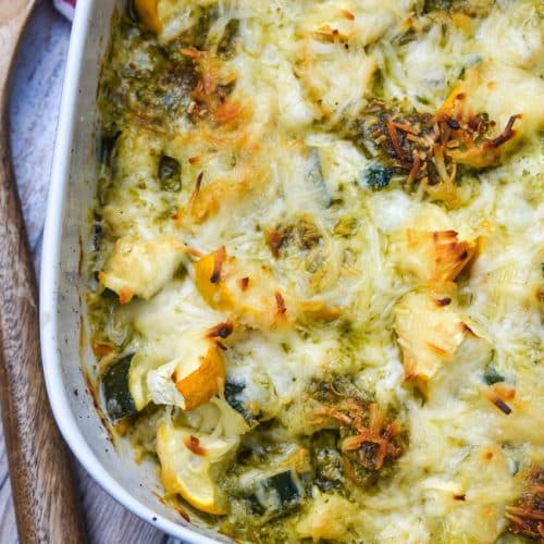 cheesy pesto chicken bake with squash on a white casserole dish
