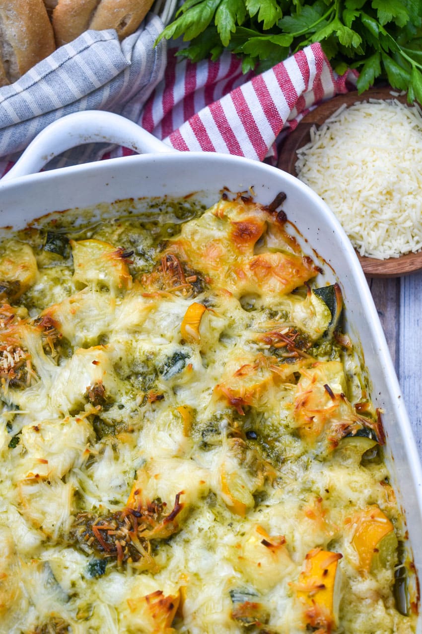 cheesy pesto chicken bake with squash on a white casserole dish