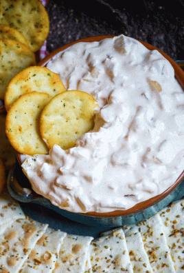 smoked onion dip shown in a blue glazed terra cotta bowl with three pita crackers stuck in it