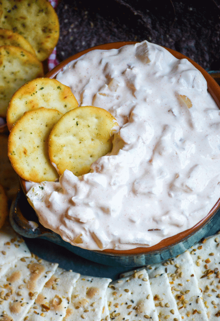 smoked onion dip shown in a blue glazed terra cotta bowl with three pita crackers stuck in it