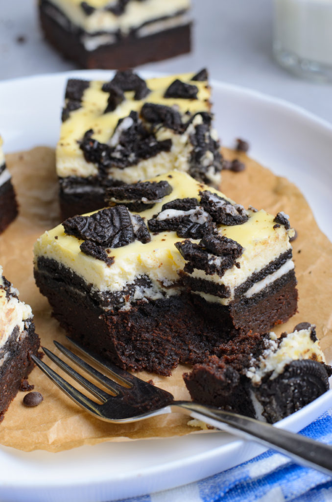 an oreo cheesecake brownie with a bite removed with a silver fork on the side