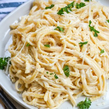 Instant Pot alfredo sauced pasta on a white plate with fresh parsley garnish