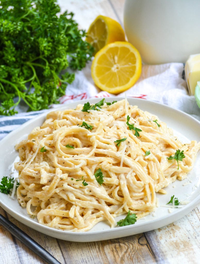 Instant Pot alfredo sauced pasta on a white plate with fresh parsley garnish