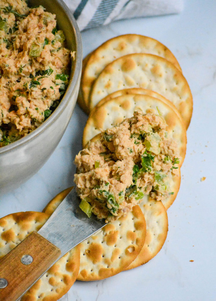 salmon salad spread shown on top of a row of fanned out water crackers