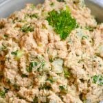salmon salad spread in a grey bowl topped with fresh parsley leaves
