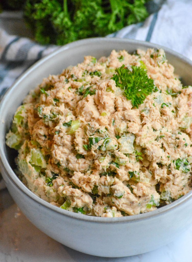 salmon salad spread in a grey bowl topped with fresh parsley leaves