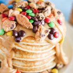 a stack of monster cookie pancakes on a white plate