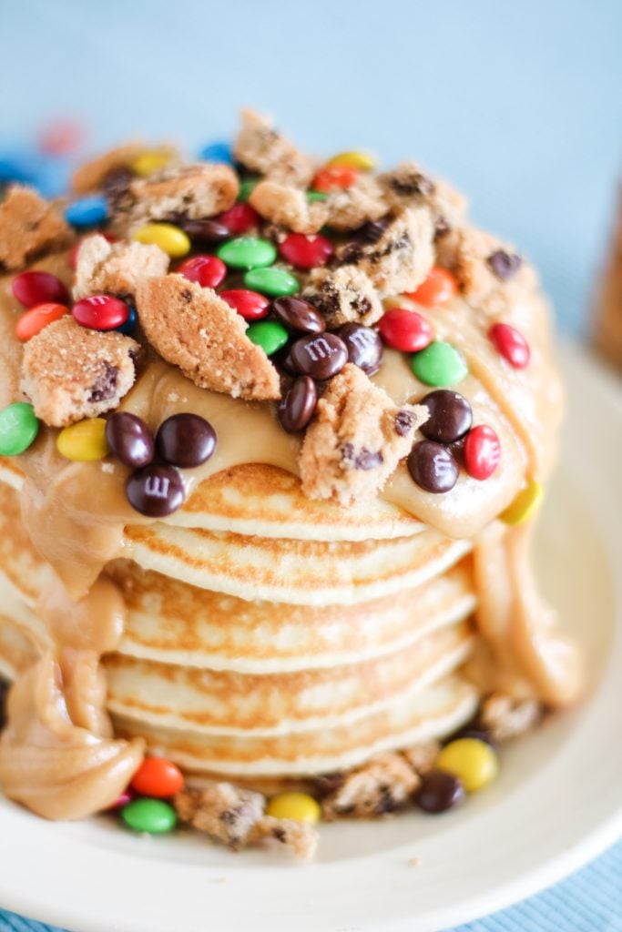 a stack of monster cookie pancakes on a white plate