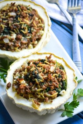 stuffed patty pan squash on a white platter with green herbs on the side
