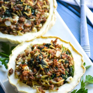 stuffed patty pan squash on a white platter with green herbs on the side