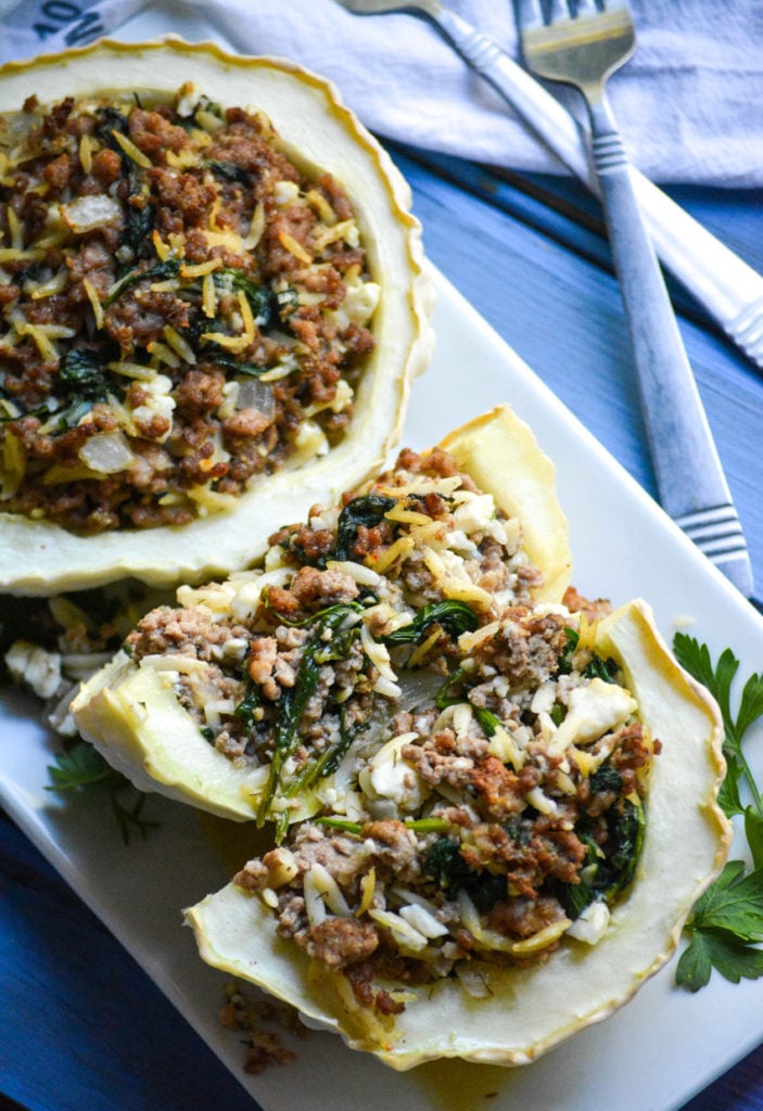 stuffed pattypan squash on a white platter with green herbs on the side