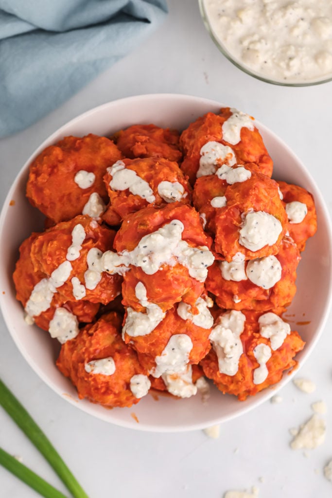 buffalo chicken meatballs drizzled with blue cheese sauce and piled in a white bowl