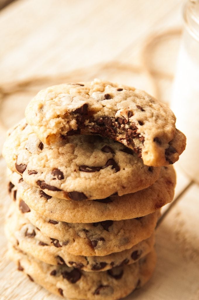 a stack of homemade chocolate chip cookies with a bite taken out of the top one