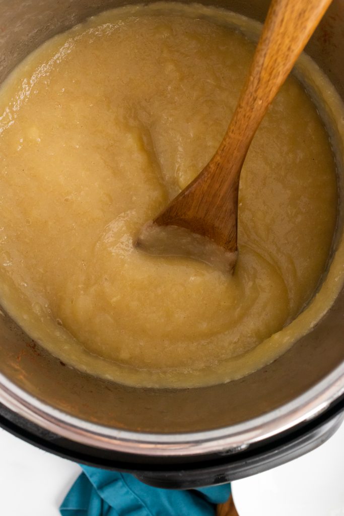 a wooden spoon in Instant pot pear sauce inside the bowl of pressure cooker