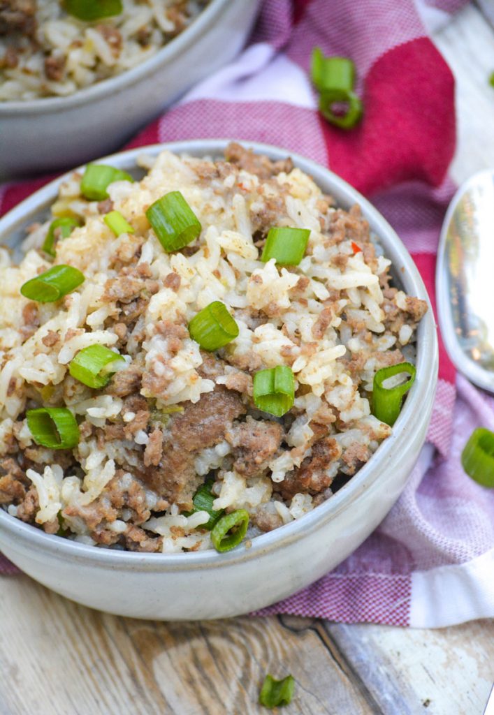 two gray bowls filled with ground beef, sausage & rice casserole topped with sliced green onions