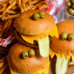 three monster burgers stacked together on a wooden cutting board