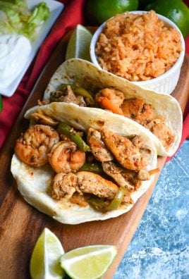 Texas fajitas arranged on a narrow wooden cutting board with a small bowl of spanish rice